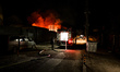 A rescuer stands near a fire truck during firefighting efforts in the private sector follo...
