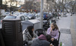 Iranian youths eat fast food as they sit on a sidewalk during New Year shopping in norther...
