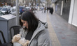A young Iranian woman hugs her pet while standing on a sidewalk during New Year shopping i...