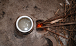 An elderly woman cooks rice on a newly built clay wood-fired stove in her house veranda wh...