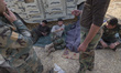 Iraqi Kurdish Peshmerga fighters rest next to an armored military vehicle near the city of...