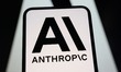 The logo of Anthropic is displayed on a smartphone screen in front of another of the compa...