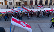 People hold a large Belarusian flag while attending a march on Freedom Day in Warsaw, Pola...