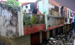 Indian residents of a flood affected area stand on their balcony to get daily needs from a...
