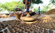 An Indian potter makes earthen lamps on a potter's wheel in a workshop as the preparations...