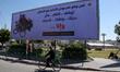 a man walking past a banner carrying the writing in Arabic "we declare our full support fo...