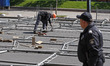 Workers prepare the official fan zone of the the Eurovision Song Contest, while a policema...