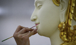 Thai official painters work on a deity sculpture which will be used to decorate the royal...