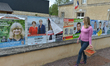 A woman passes in front of election posters with local candidates on display in front of D...