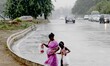  Pedestrians look on the road as they are protecting in the umbrella in the pre-monsoon ti...