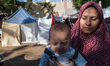 A mother holding her baby at the refugee camp set up behind the Al-Shifaa Hospital. Lack o...