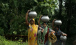 Village living women hold drinking waters atop their head as they return back home after c...