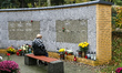 Woman sitting in front of columbarium with urn with the ashes of a dead family member on t...