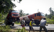 TEMANGGUNG, INDONESIA - AUGUST 28: Men use chains to try and right a molasses truck overlo...