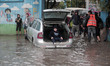 Palestinian school children walk in a flooded street during heavy rain in Gaza City on Nov...