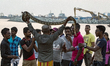 A Sri Lankan snake charmer lifts up a full-grown pet python reptile over his head enticing...