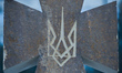 A view of a sign with a gold trident, the official coat of arms of Ukraine, on a cross-mon...