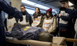 Foreign residents are shown how to prepare a stretcher using a blanket to rescue their fei...