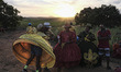 A group of costumed women reacts to a hug from a friend while they await the presentation...