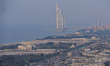 A panoramic view of the Burj al-Arab luxury hotel and the area around at night, from the M...