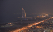A panoramic view of the Burj al-Arab luxury hotel and the area around at night, from the M...