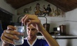 A Bulgarian man inspects an alcoholic raki extract at a home alcoholic raki, distilling in...