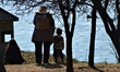 A woman and her children look at swans next to an artificial lake during a warm day as the...