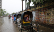 Rickshaw pullers sit inside their rickshaws passing lazy time during the rainfall in Dhaka...