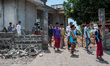 Muslim men walk home after Friday prayers around the damaged mosque in Kokok Putik Village...