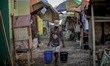 An elderly man fetches two buckets of water at a relocation site for typhoon victims, one...