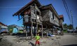 A young boy plays with a ball outside a damaged house, one year after Typhoon Haiyan hit,...
