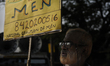 An old man with a banner supporting men's movement during the celebration of International...