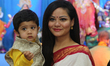Bengali Hindu woman and her child pose for a photo (with the idol of the Goddess Durga in...