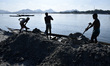 Labourer unloading sand from boat extracted from Aai river, in Bangaigaon,Assam, India on...