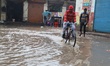 Pedestrians walk through a waterlogged street following heavy rains in Gurgaon, Haryana, i...