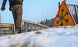 Man walking along the slippery pavement and road warning sign  is seen in Gdansk, Poland o...