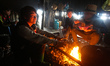 Porters in a self made hut warming up and eating, they are carrying parts for the new cabl...