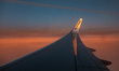 Wing view from the window of an airliner during the magic hour after the sunset. The aircr...