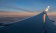 Wing view from the window of an airliner during the magic hour after the sunset. The aircr...
