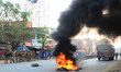police officials stands near a fire , as samajawadi party supporters protest and set fire...