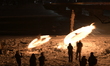 Participants perform a fire dance and create a fire ring by swing bales of burning straw d...