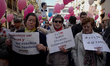 A woman holds a placard reading 'Equal, Different, Complementary' during the demonstration...
