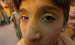 A visually impaired student of ‘Kamla Mehta School’ gets his face painted with coloured po...