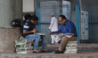 Distributors sit on a pile of Newspapers as they wait for the delivery boys under a bridge...