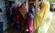 Kashmiri people stand in line to cast the votes outside polling booth in Shadipora area of...