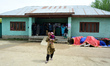 A woman carrying her child as Kashmiri people stand in line to cast the votes outside poll...