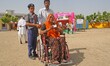 Indian young volunteers help a physically challenged voter on a wheelchair after cast  vot...