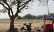An indian man takes rest on his scooter under the shadow of a tree during a hot day in All...