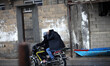 Two young men covering her head from low air cool and go by motorbike in refugee Beach on...