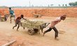 Workers carrying molded muddy bricks to the fireplace at a brick field in Haripur, Sylhet,...